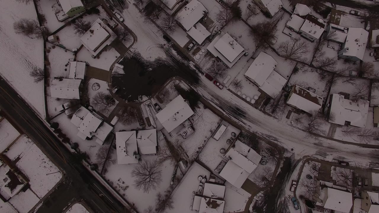 Top-down aerial view of snow-covered houses and roads.
