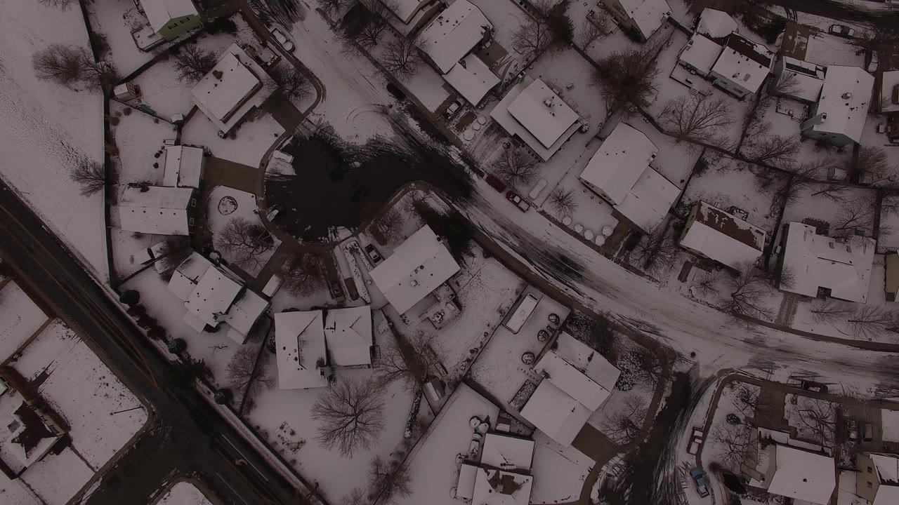 One second in, the overhead Jefferson County view holds on snow-covered rooftops, curved side streets, driveways, leafless trees, and no visible people.