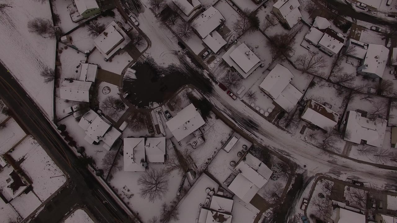 Overhead aerial view in Jefferson County, Colorado showing snow-covered houses, bare trees, curved roads, and no visible people at the start of the clip.