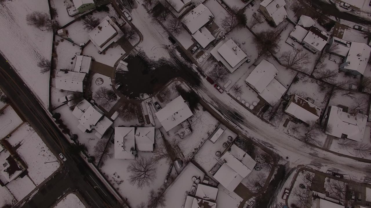 Aerial straight-down frame in Jefferson County, Colorado, with white roofs, fenced yards, driveways, leafless trees, a dark road at the edge, and no visible people.