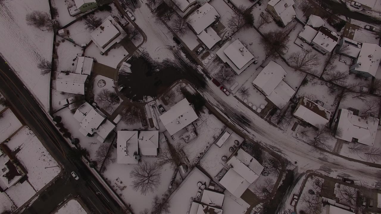 Snowy houses and a dark road seen from above.
