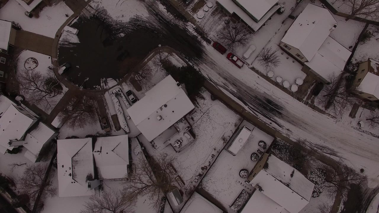 Overhead view of snowy houses and a curved residential street.