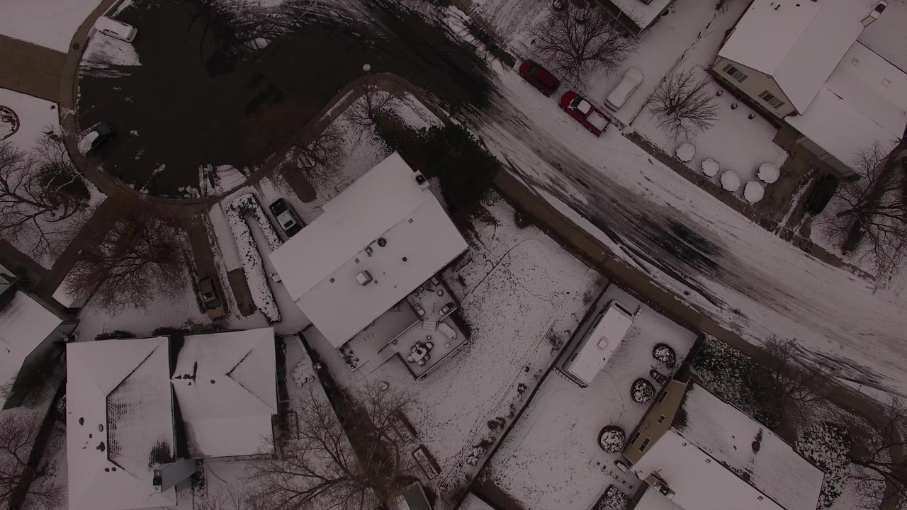 Overhead view of snowy houses and a curved residential road.