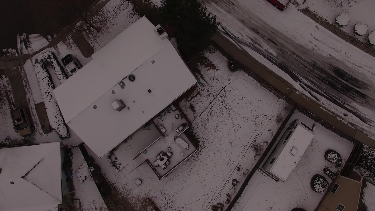 Overhead view of a snow-covered house roof beside a slushy road.