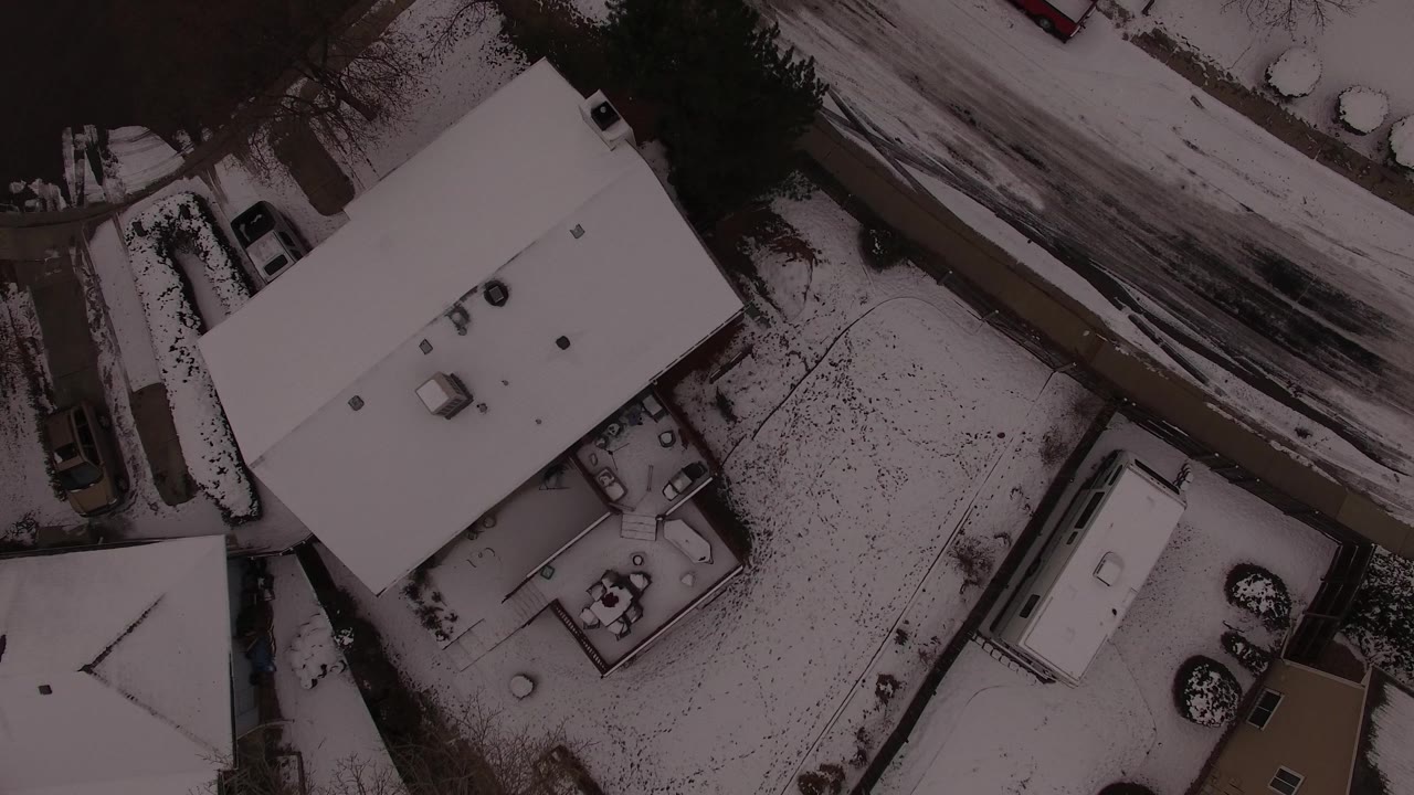 Aerial frame in Jefferson County, Colorado with the large white roof centered, a fenced or bordered yard below it, a slushy road above, and no visible people.