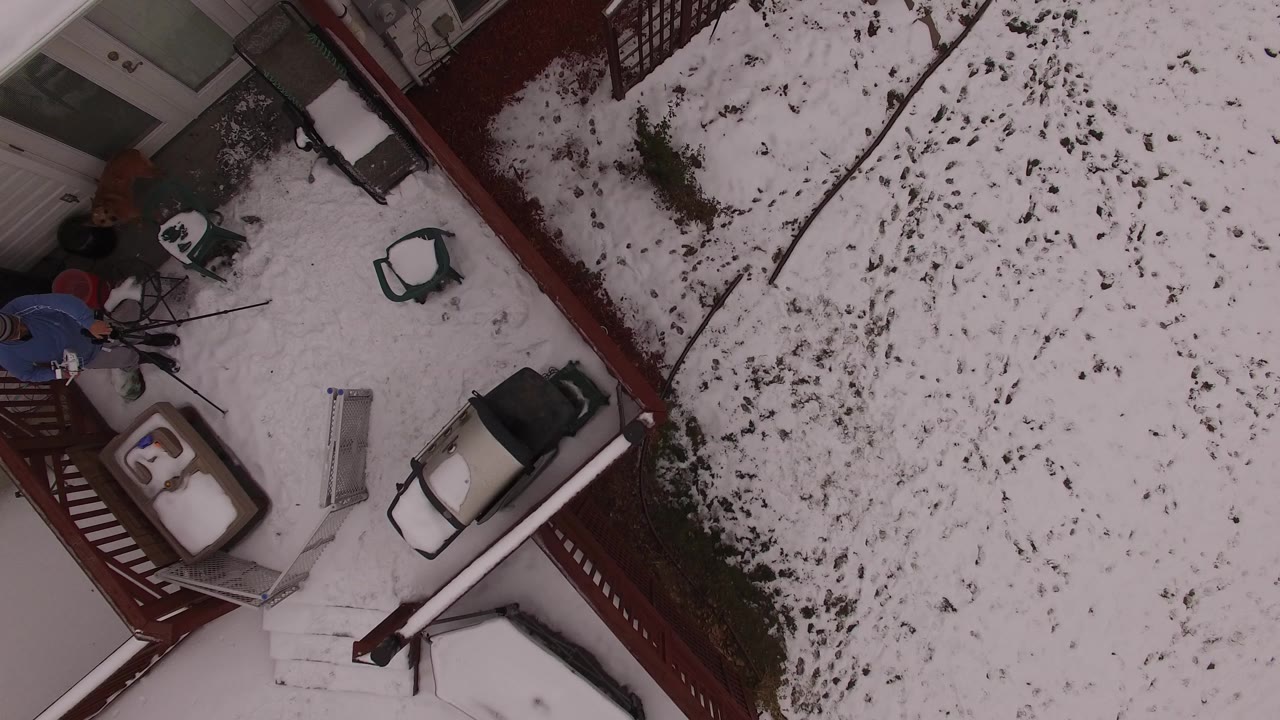 Overhead view of a snowy yard beside a house and deck.