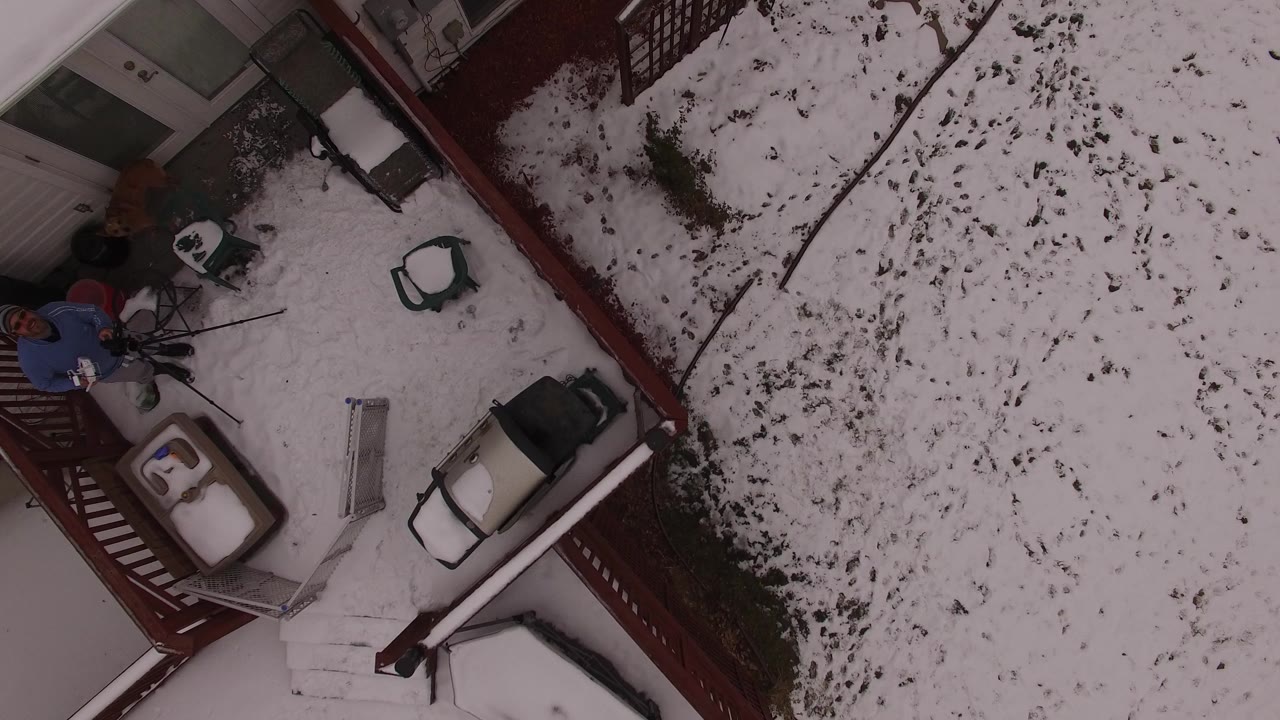 Overhead snowy deck beside a yard with a person near the railing.
