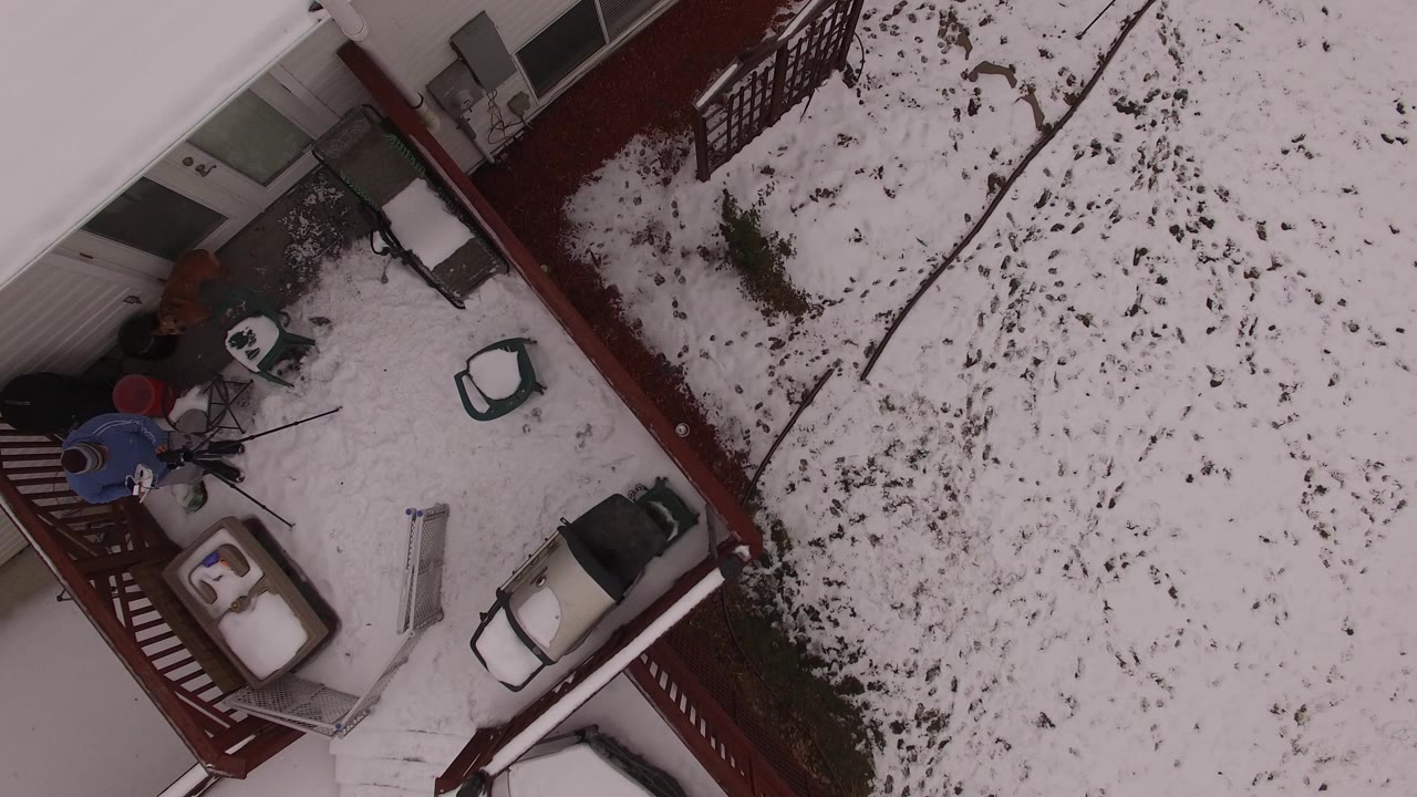 Top-down view of a snowy backyard beside a red deck.