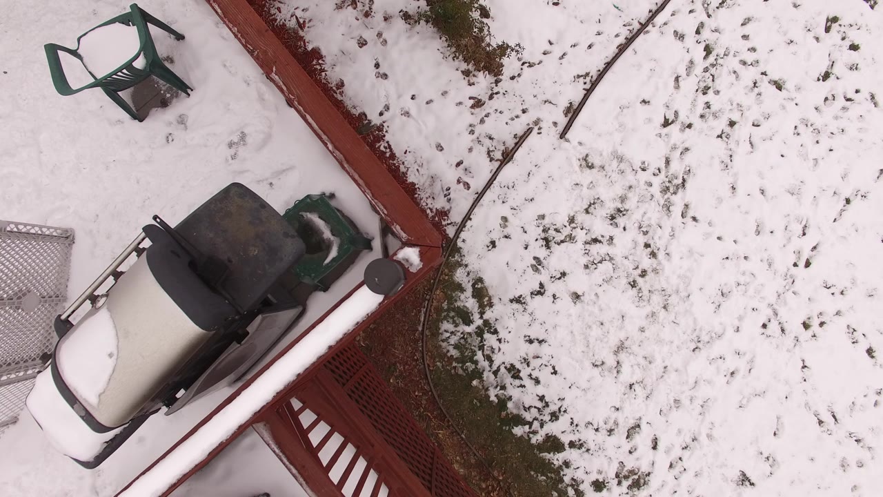Overhead snowy yard with red deck edge, outdoor furniture, and grill area
