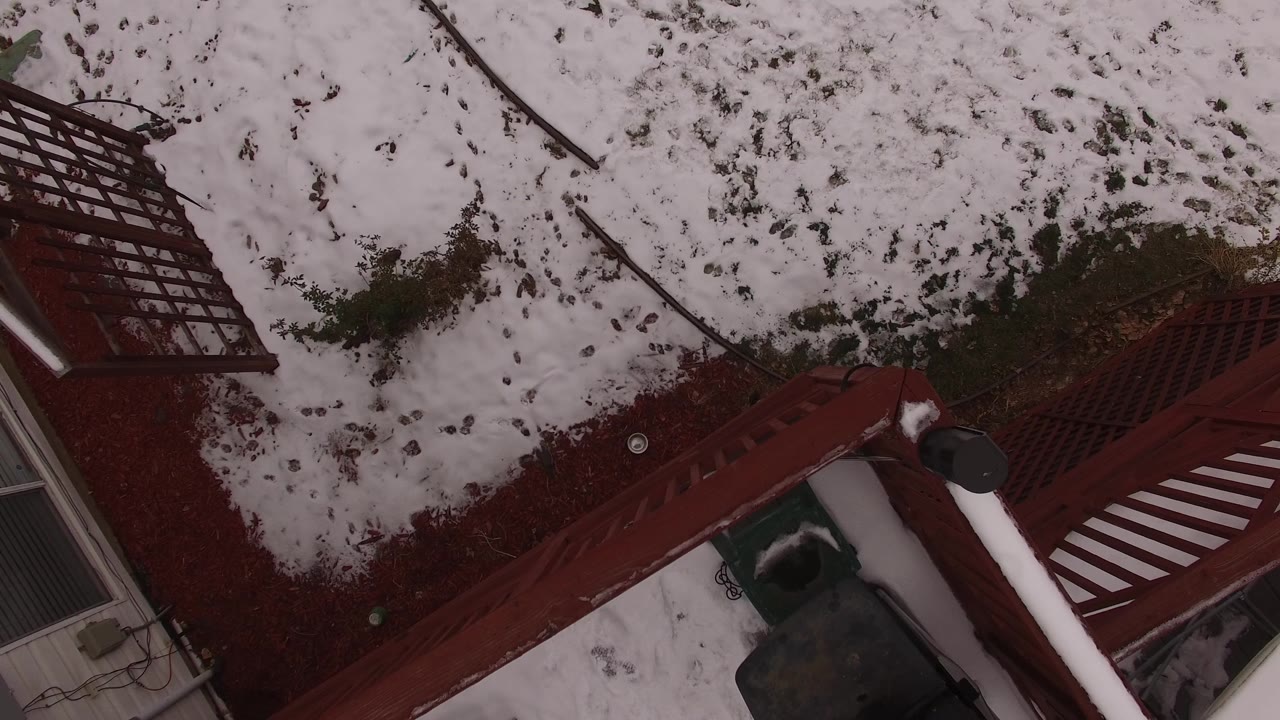 Steep downward view in Jefferson, Colorado of red deck rails crossing patchy snow and exposed winter ground, with no visible people.