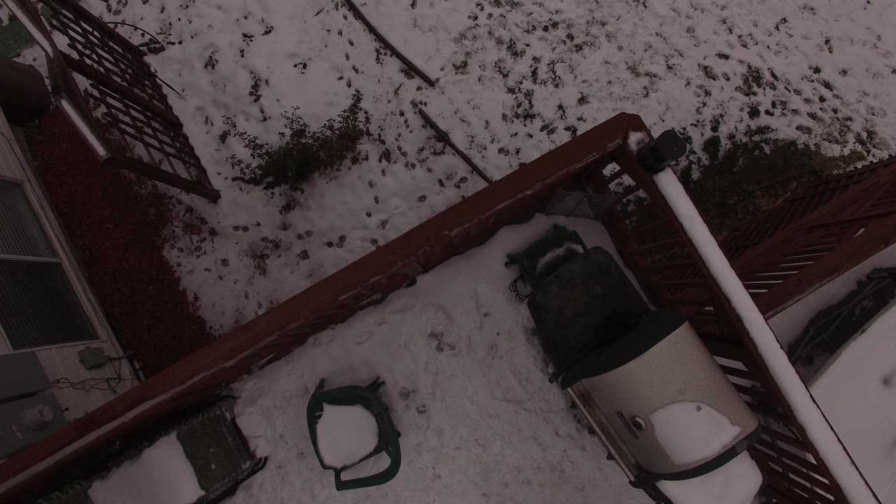 Overhead view in Jefferson, Colorado of a snow-covered backyard crossed by a red fence, with patio furniture and part of a house edge visible, no visible people.