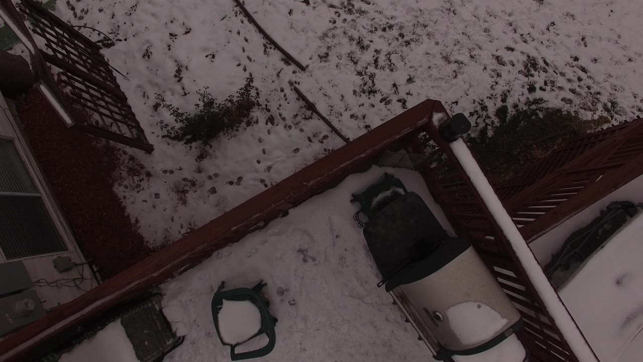 Diagonal red fence over a snow-covered backyard from an aerial angle