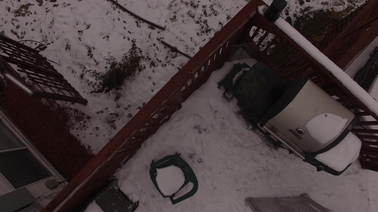 Overhead view of a snowy patio with deck rails and outdoor furniture.