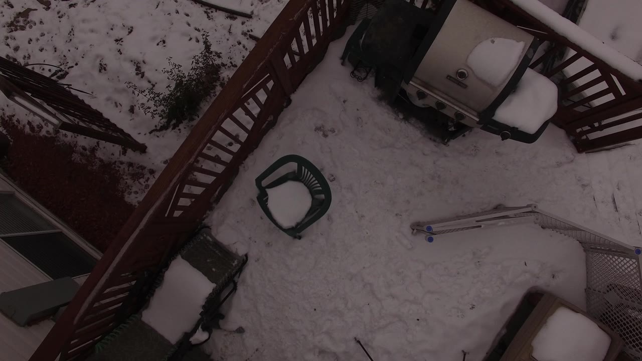 A high angle frame shows the Jefferson, Colorado deck with snow across the floor, a green patio chair near center, a covered grill near the railing, and no visible people.
