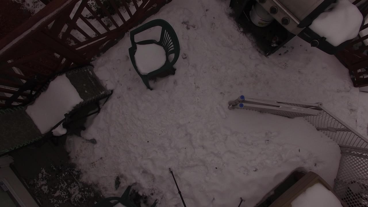 Overhead view of a snow-covered terrace in Jefferson County, Colorado, with red deck railing, green patio seating, and no visible people.