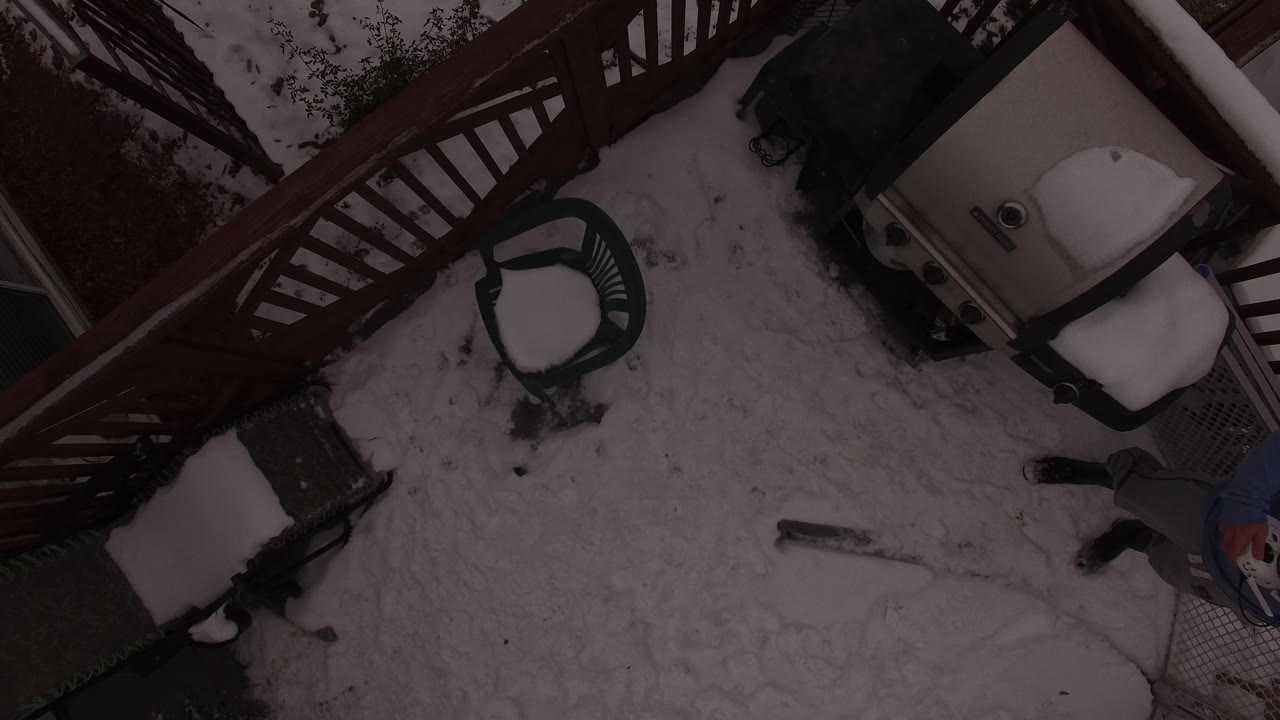 Overhead Jefferson, Colorado view with the red railing crossing the top, snow-covered chairs and a covered grill near the right side, and a person partly visible near the bottom edge.