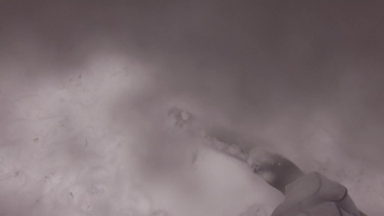A boot and lower leg remain partly visible over packed snow, with the Jefferson County, Colorado winter surface filling most of the frame.