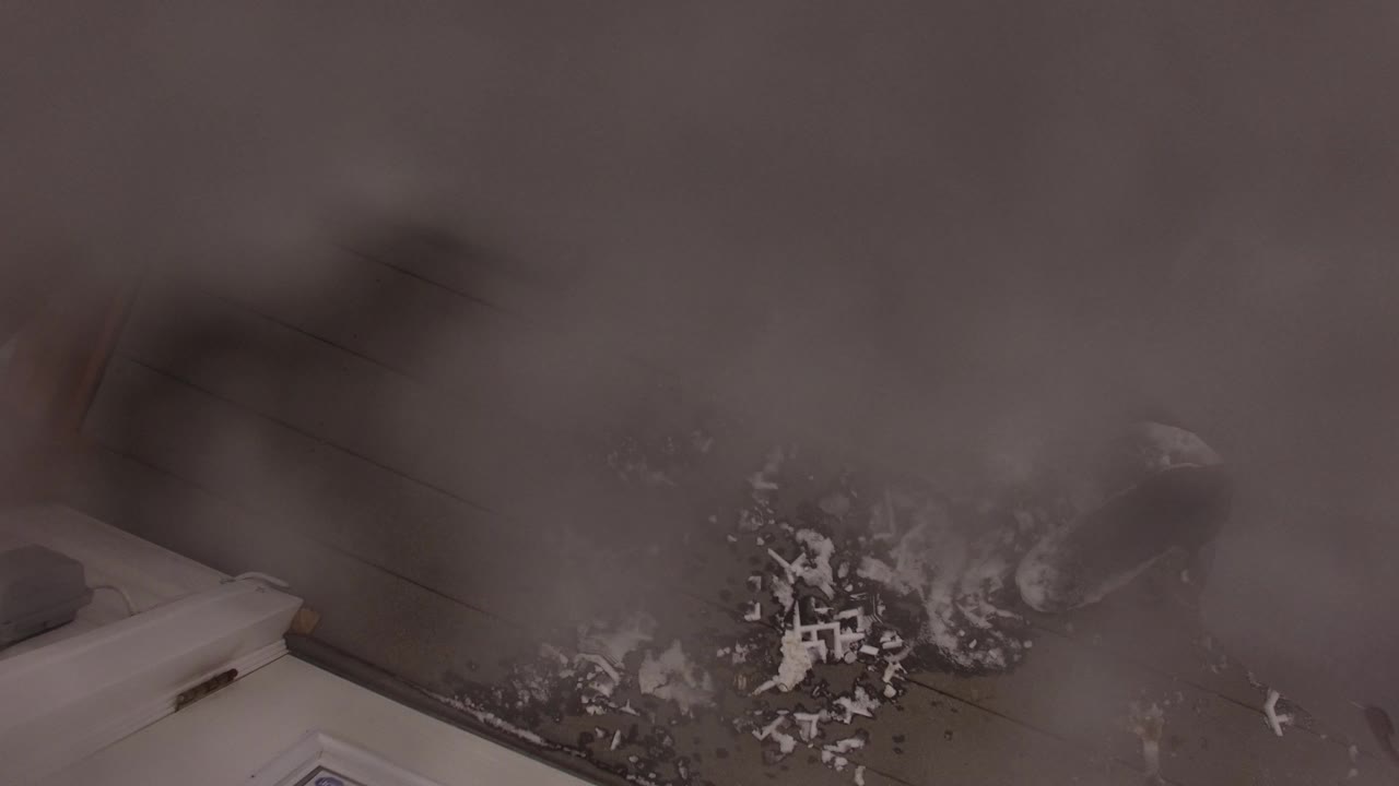 Blurred downward view of dirt and debris on a floor beside a white appliance edge.