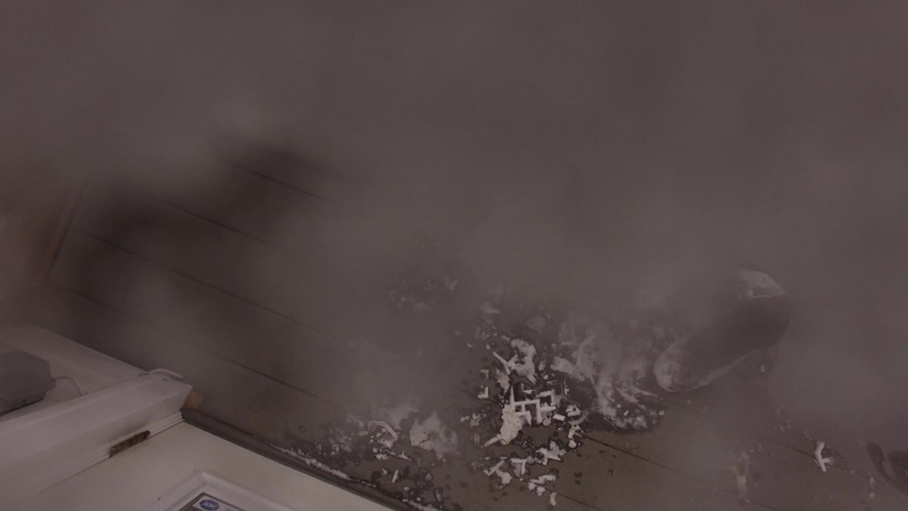 The second frame holds on a tilted Jefferson, Colorado interior floor with scattered dirt, a white appliance corner, and heavy blur across the upper part of the view.