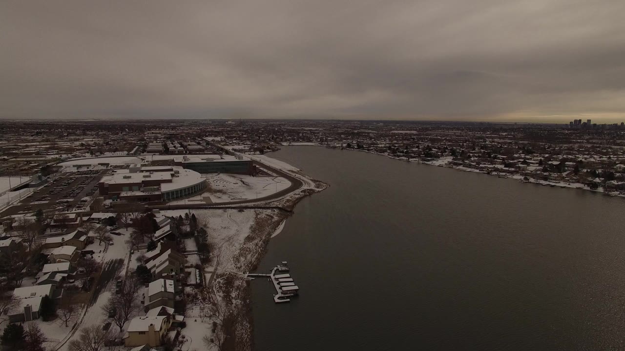 Snow-covered lakeside neighborhood under a gray sky.