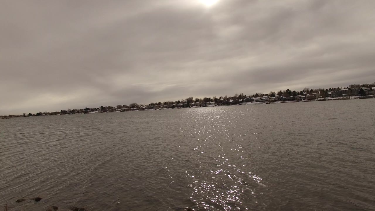 Wide water view with sun reflection and distant shoreline