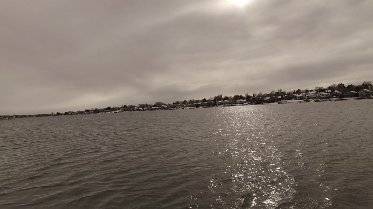 Wide water view with distant snowy shoreline and bright glare