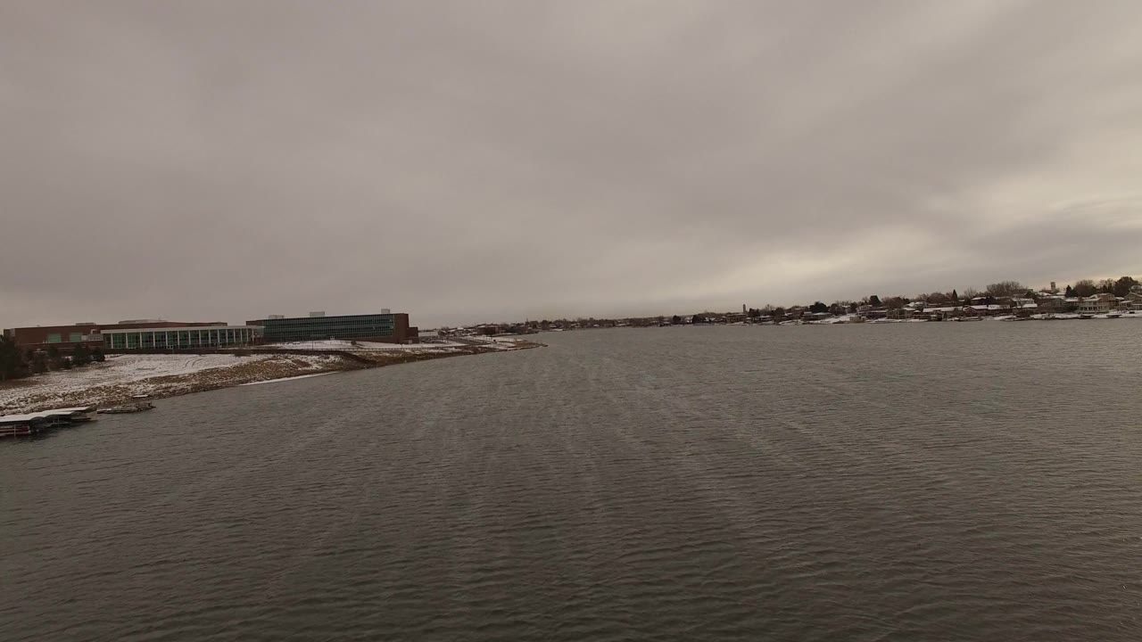 Gray water and low shoreline buildings beneath heavy clouds.