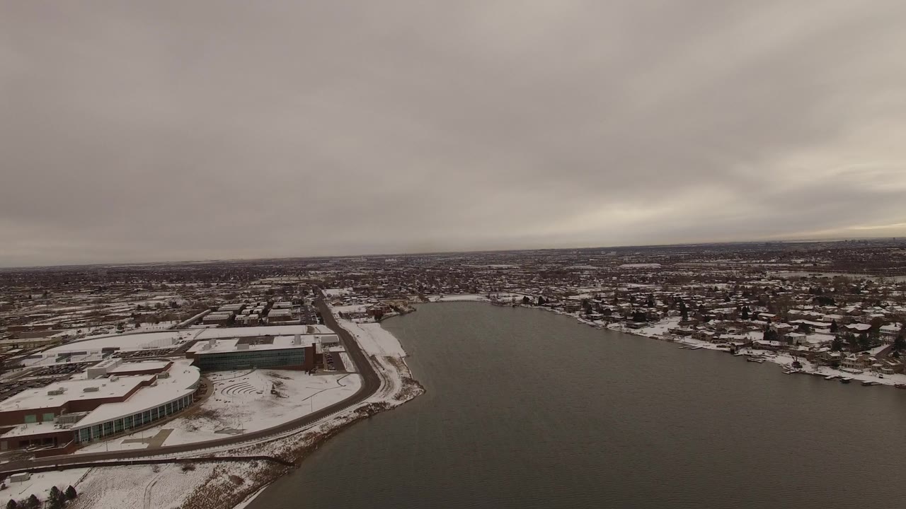 Wide aerial of riverfront buildings under a gray winter sky