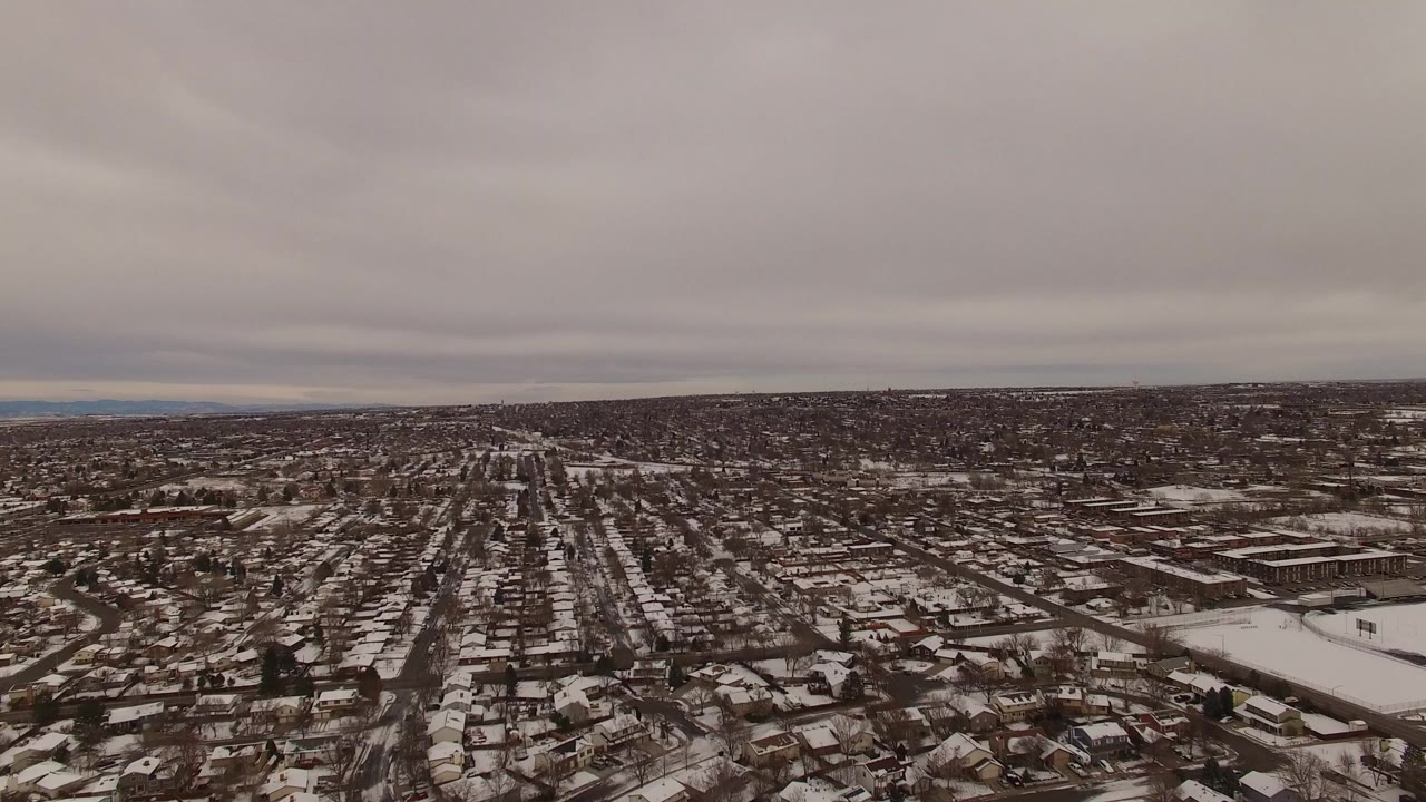 Opening aerial frame over Jefferson County, Colorado, with gridded residential streets, snow-dusted roofs, bare trees, and no visible people.