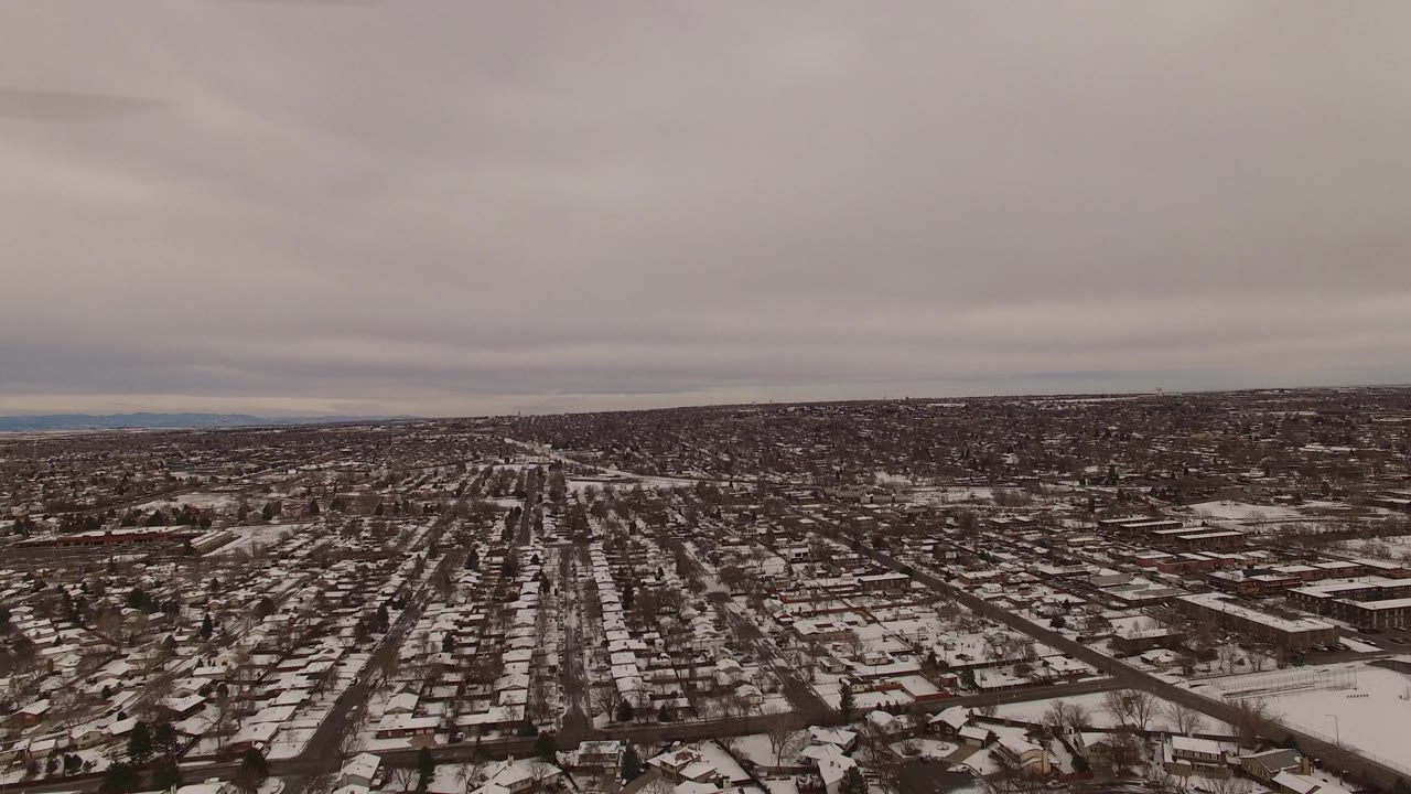 Snow-covered neighborhood seen from above under a gray sky.