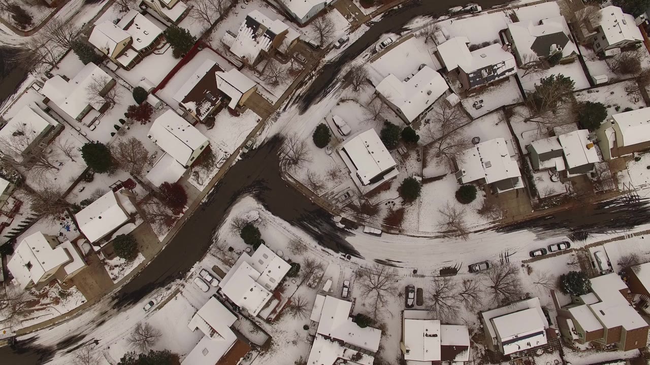 Overhead view of snowy houses and curved residential streets.