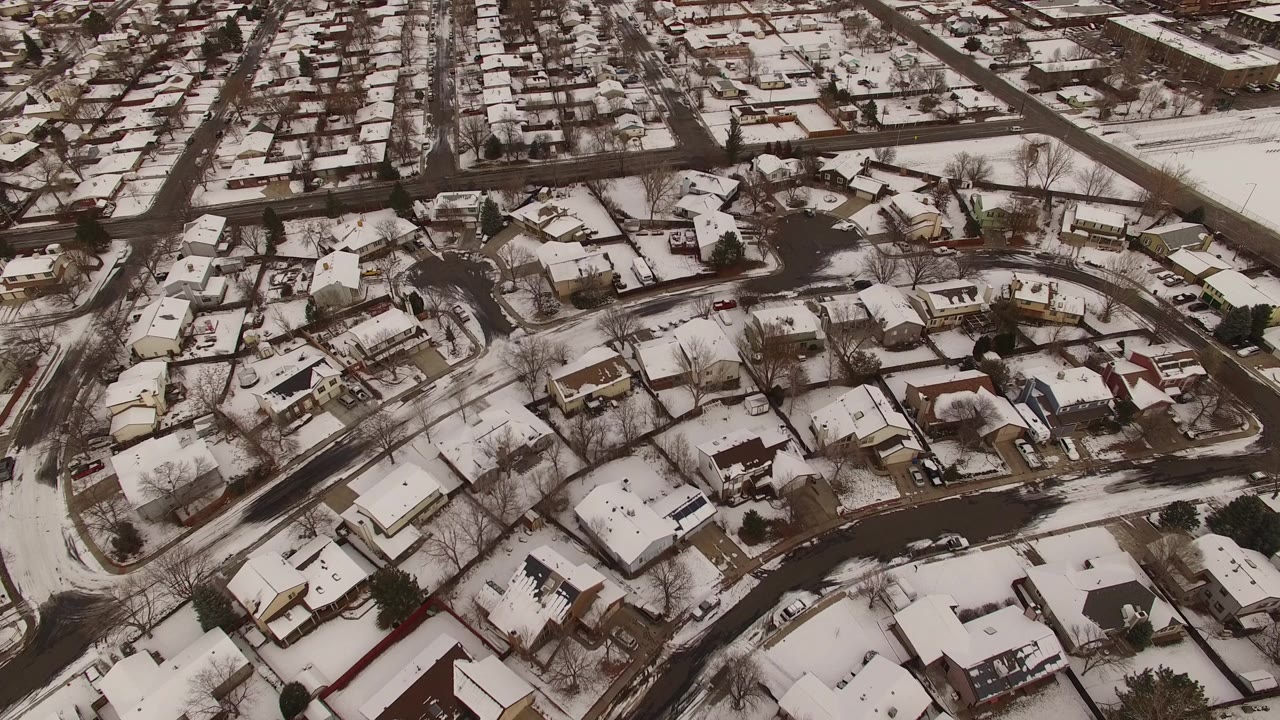 Snow-covered suburban homes and curving streets seen from above.