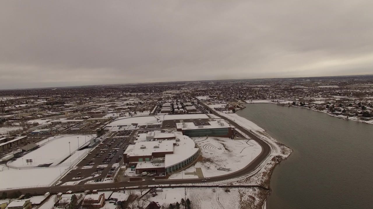 Aerial view of a snow-covered lakeside development under gray clouds.