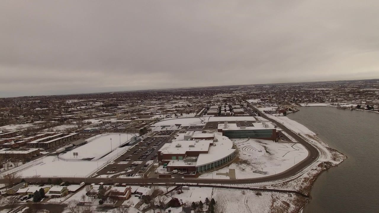 Snowy aerial view over a waterfront city area under gray clouds.