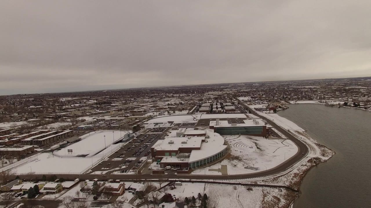 At 0:01, the Jefferson County aerial centers more tightly on the large waterfront building, curved road, snowy lots, surrounding homes, and no visible people.