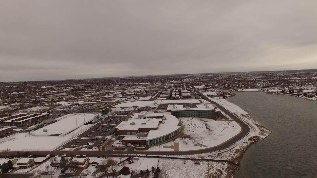 Aerial view of snowy lakeside buildings beside gray water