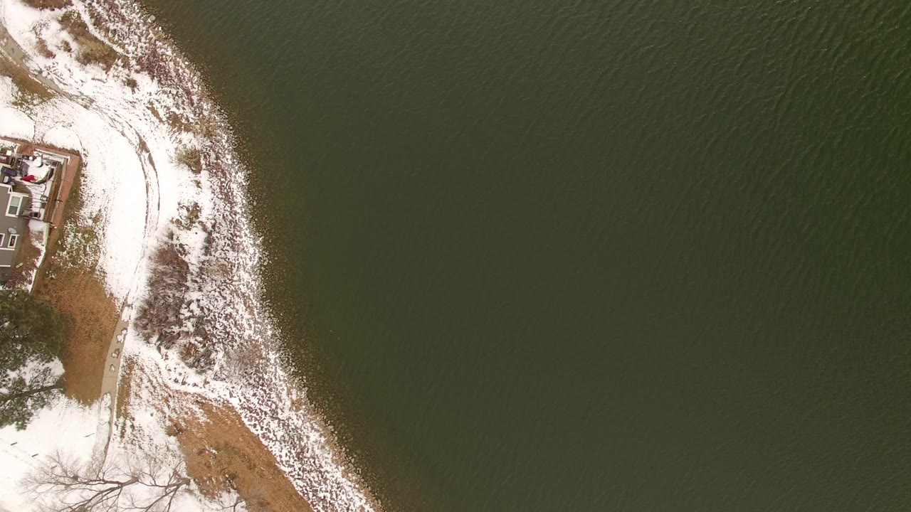 Overhead snowy shoreline beside dark green water