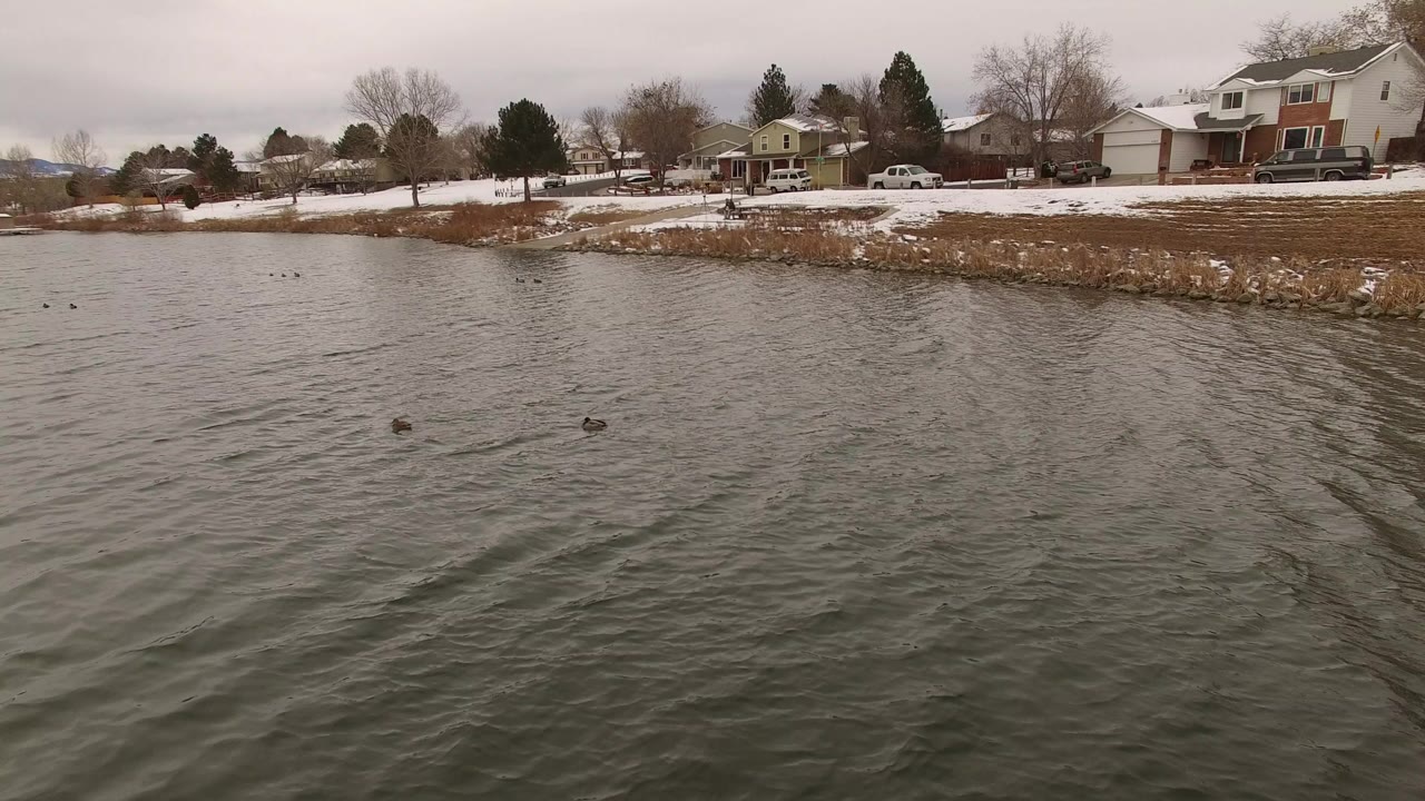 Rippling lake water with snowy residential shoreline in the distance.