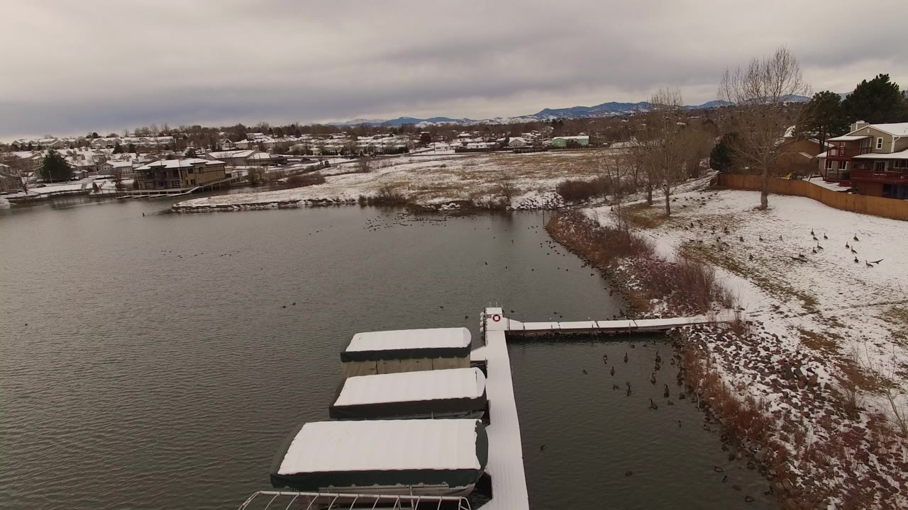 Snow-covered docks extend into a gray lake beside a snowy shoreline.