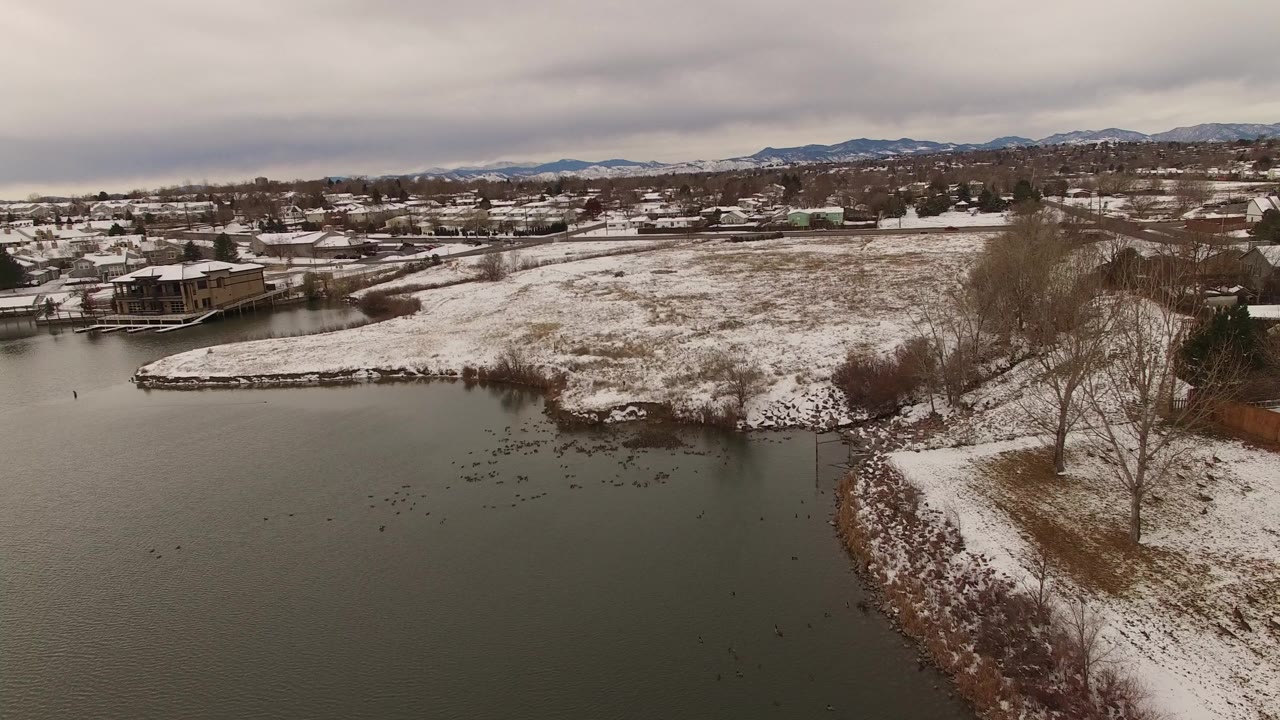 Snow-covered point beside a lake with homes and mountains beyond