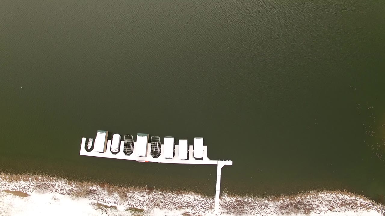 Dock with boats over dark water and snowy bank