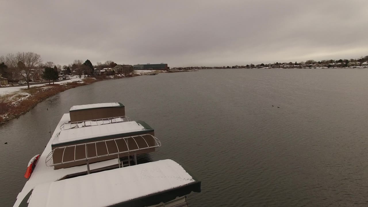 Anchored boats at the edge of a broad gray lake.