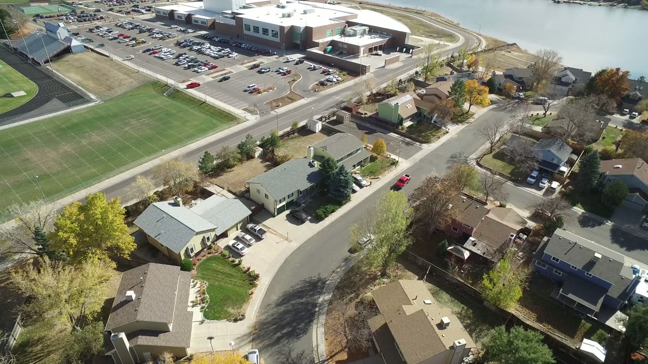 Aerial view of homes, a road, a green field, and a large building complex.