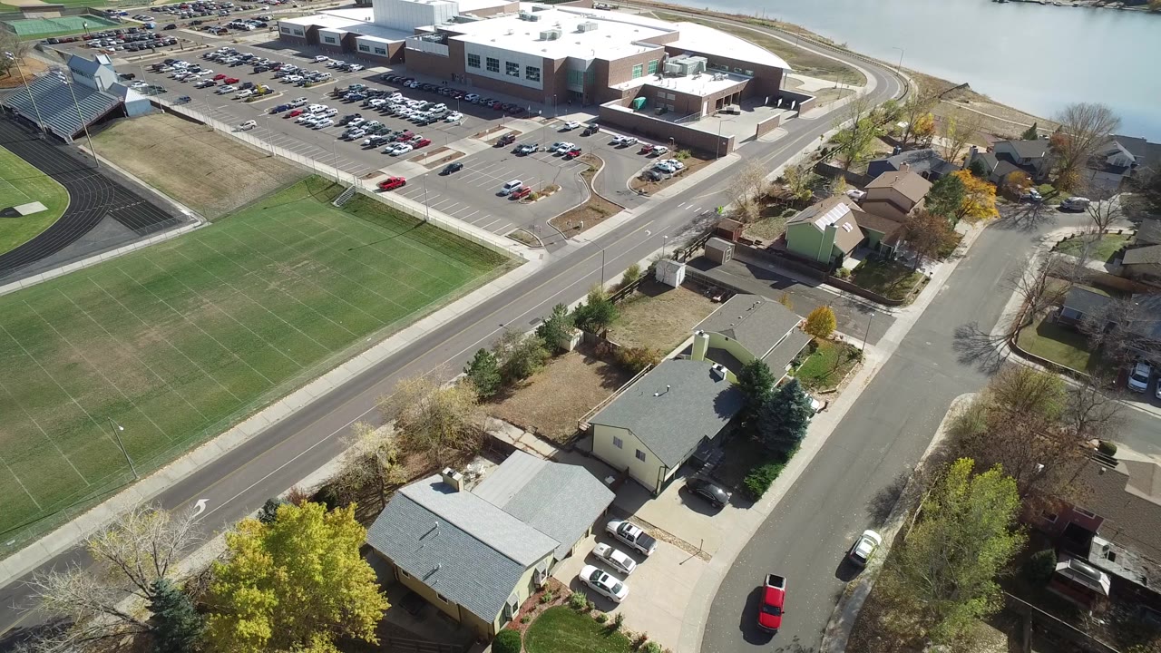 Aerial view of sports fields, homes, roads, parking lots, and water.
