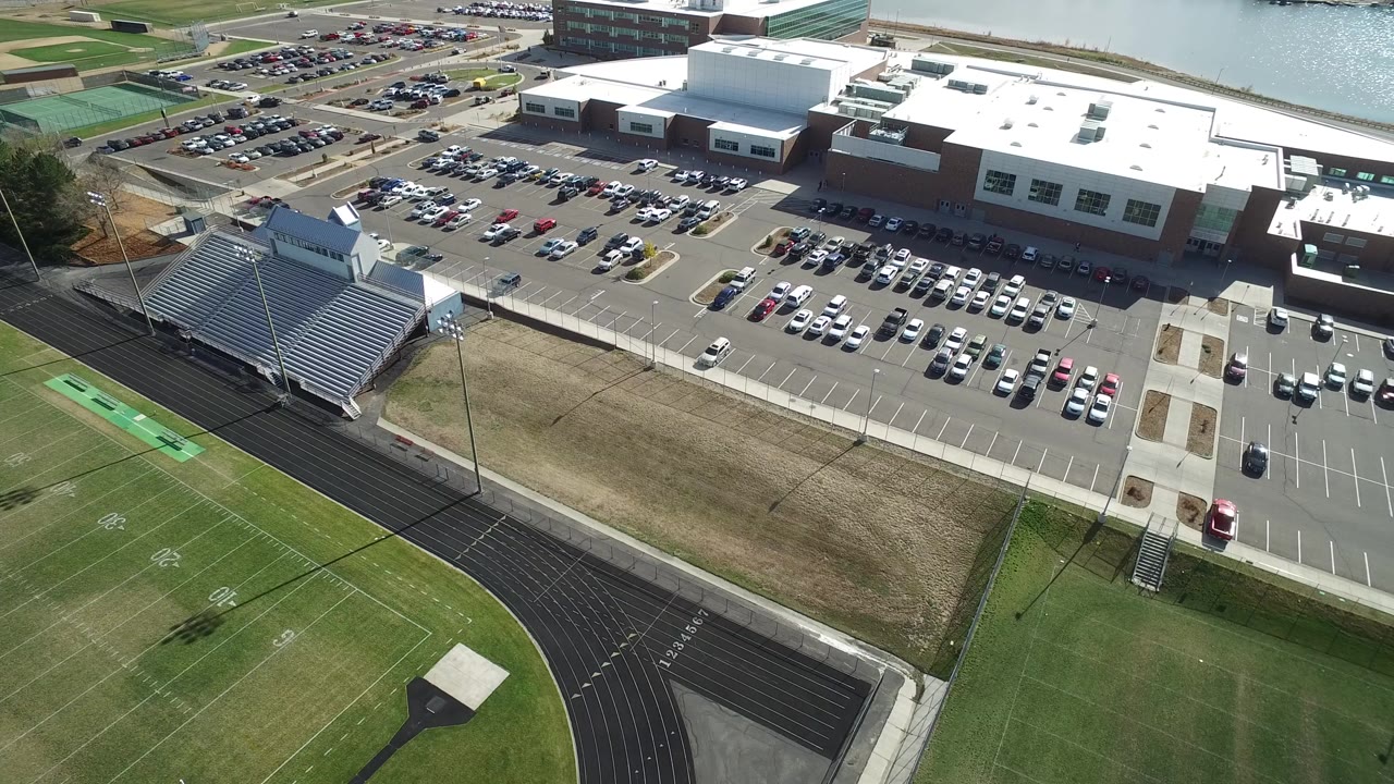 Aerial view of a large facility, parking lots, bleachers, running track, and athletic field.