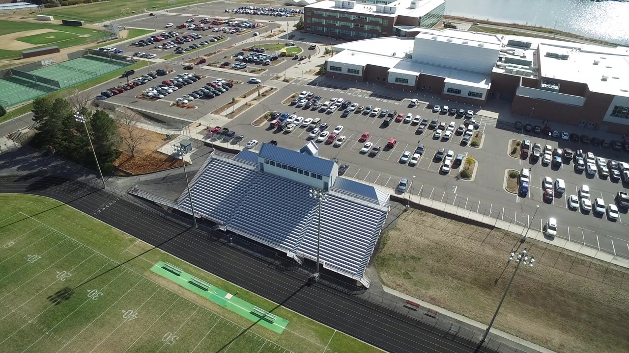 Aerial view of bleachers, football field, parking lots, and large buildings.