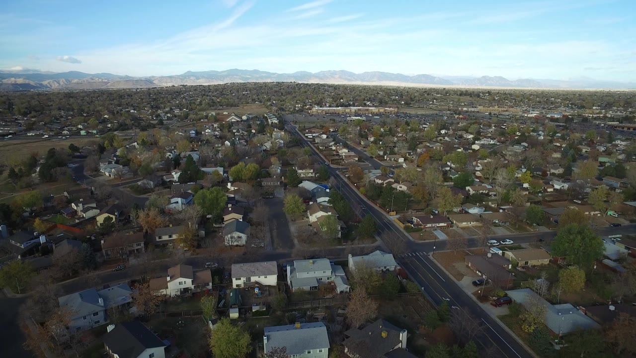 Aerial view over suburban homes and streets with mountains on the horizon