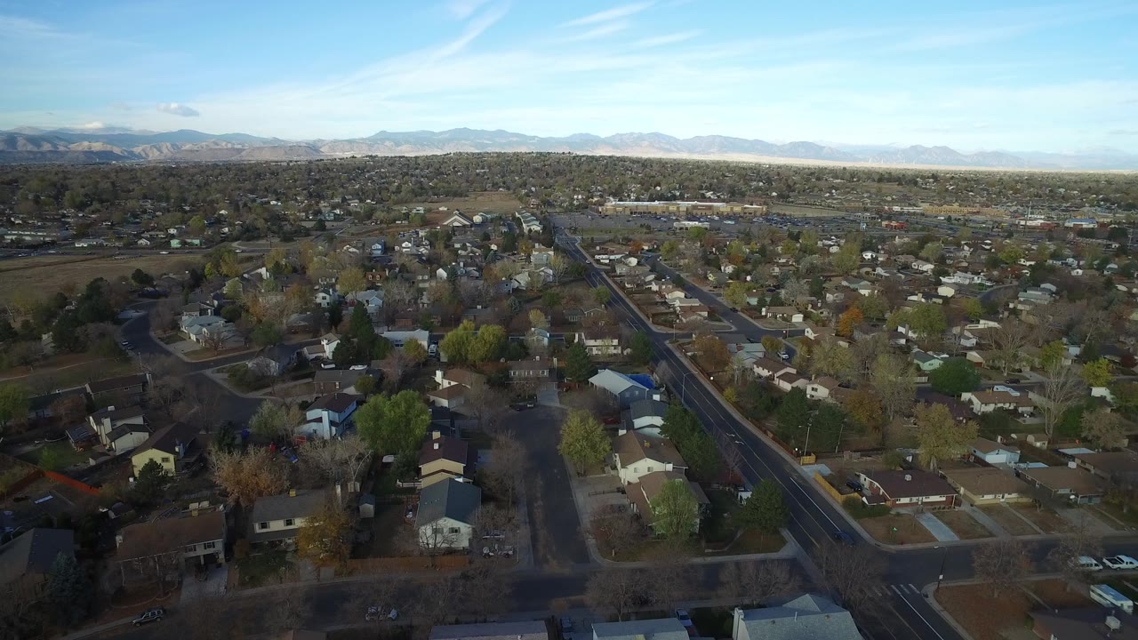 Aerial view over suburban homes and streets with mountains on the horizon.