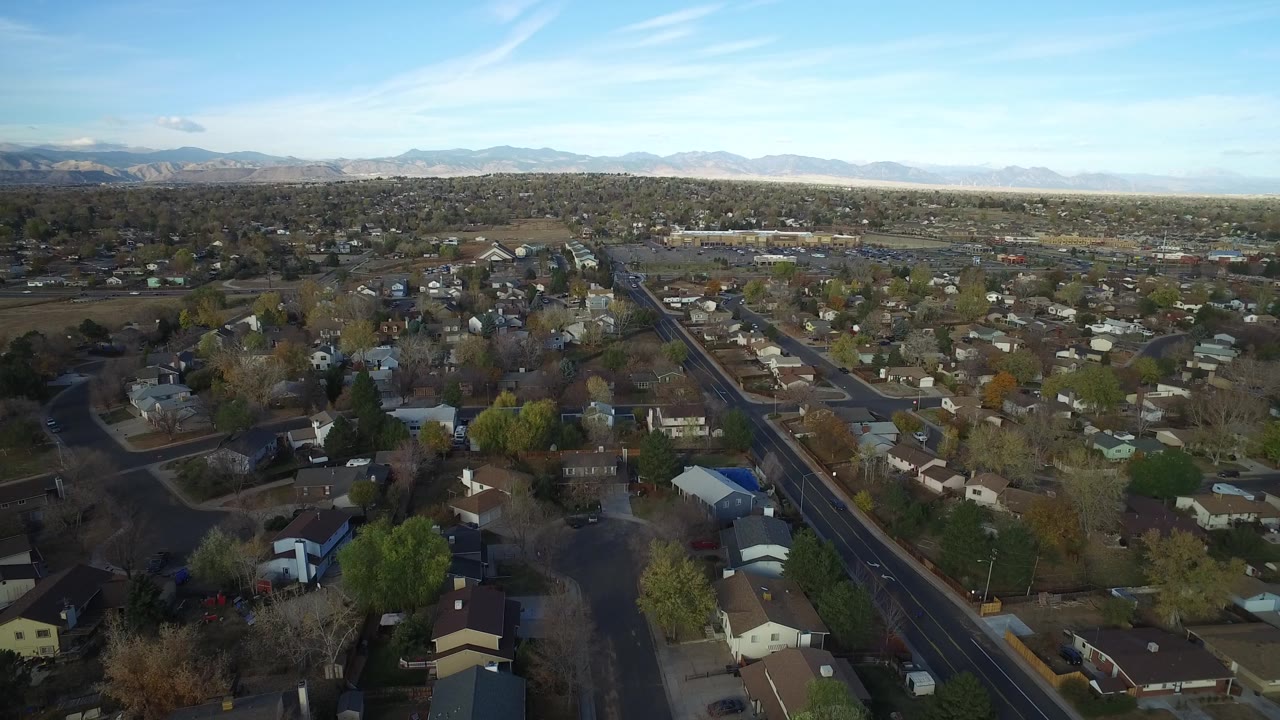 Aerial neighborhood panorama with houses, streets, trees, and horizon line.