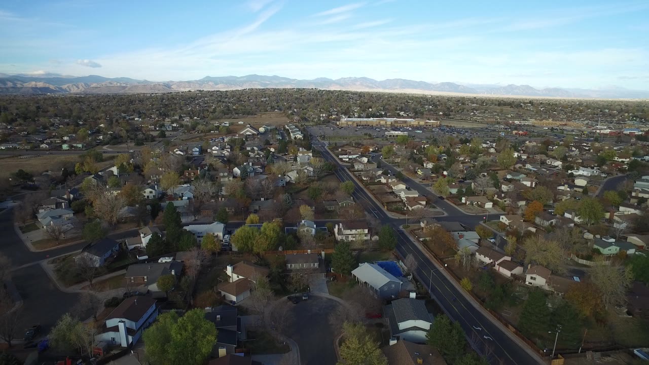 Aerial view over small houses, roads, trees, and distant mountains